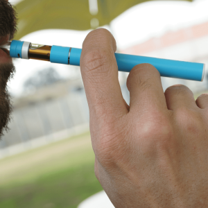 man with a beard smoking from a blue cannabis vape pen