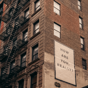 sign on the side of a new york city building asking how are you, really?