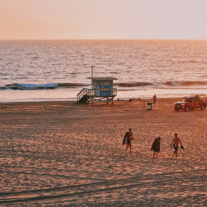 people walking on the beach at sunset