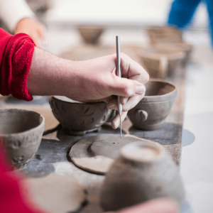 person wearing a red sweatshirt and doing pottery