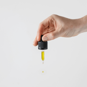 a person holding a black dropper with gold liquid