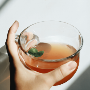 person holding a glass mug of tea