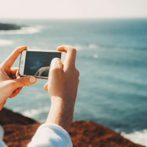 a person using their phone to take a picture of the beach