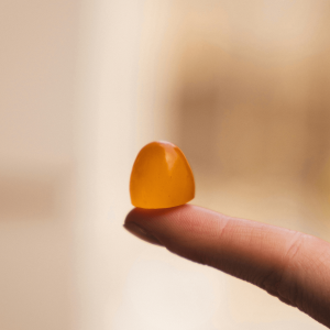 a finger holding an orange gummy