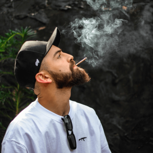 man in black hat and white shirt smoking a joint