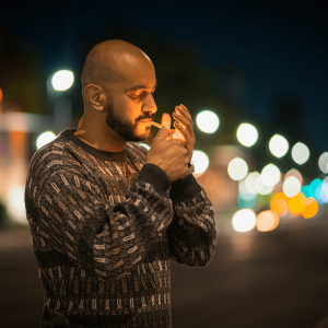 man in sweater lighting a joint