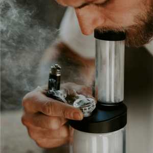 a man with a beard smoking from a glass bong