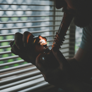 man in dark room lighting a bong