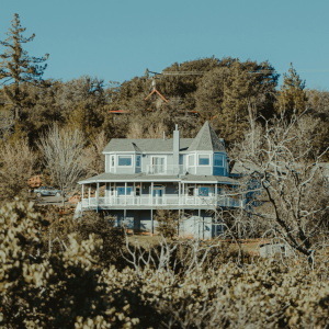 a blue house on a hill surrounded by trees