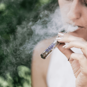 a woman smoking ground cannabis flower from a one-hitter