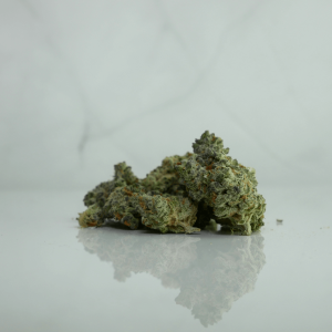 green cannabis nugs sitting on a white marble surface