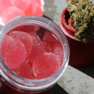 pink gummies pictured next to a grinder with cannabis flower