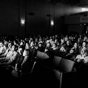 black and white image of people in a theater watching a movie