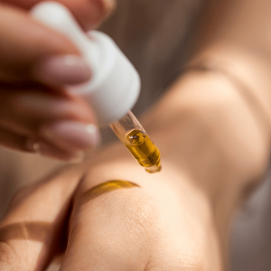 a person applying gold CBD oil from a dropper