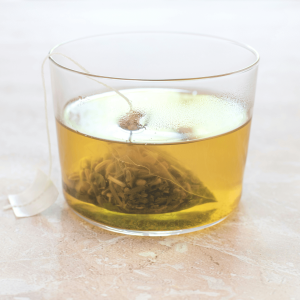 tea bag in a clear glass with gold liquid