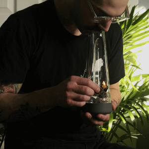 man in black shirt smoking from a glass bong