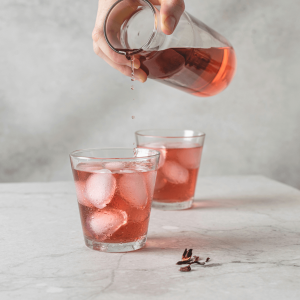 person pouring red drink in glasses