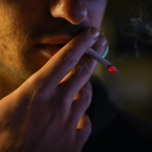 man with stubble smoking a joint