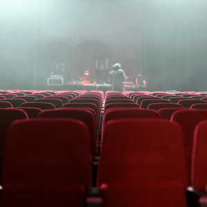 people in a smokey theater with red chairs