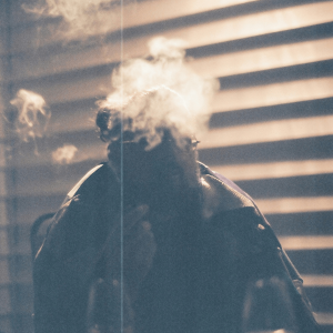 person smoking next to white blinds